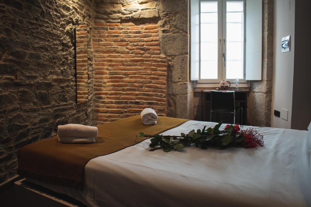 Una cama con dos toallas y flores. en Pensión A Casa do Peregrino, en Santiago de Compostela