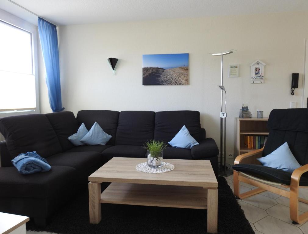 Sala de estar con sofá negro y mesa de centro en Seemöwe Whg. 8 en Cuxhaven
