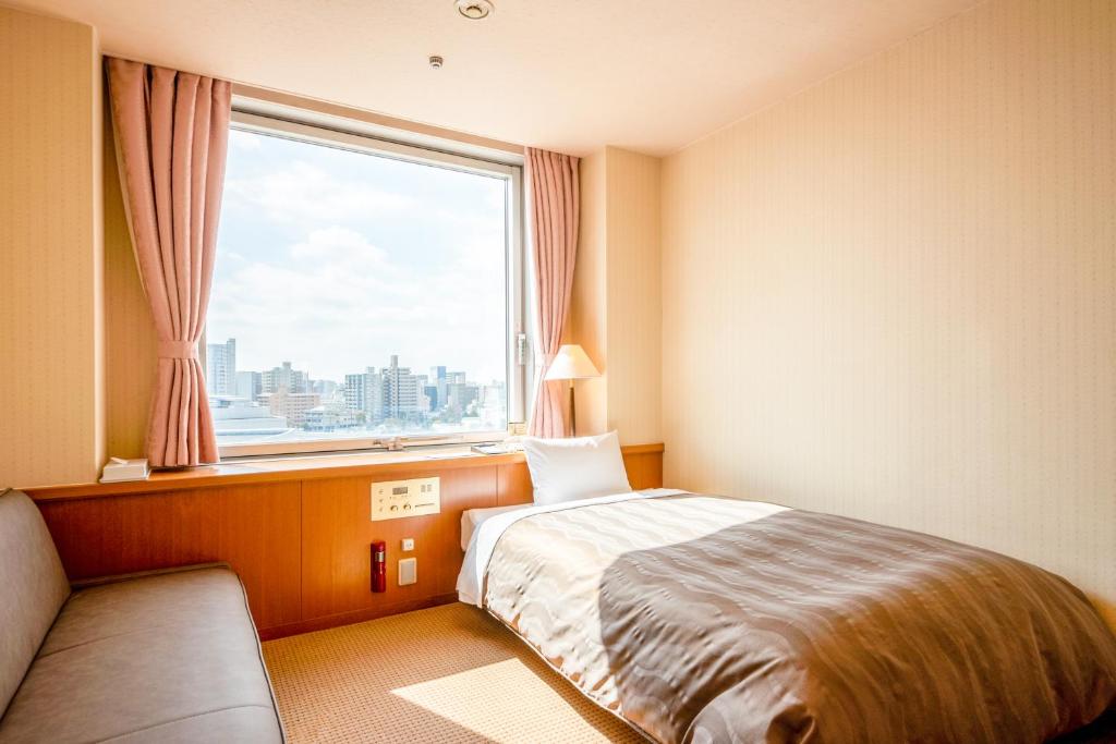 a hotel room with a bed and a large window at Hiroshima City Bunka Koryu Kaikan in Hiroshima