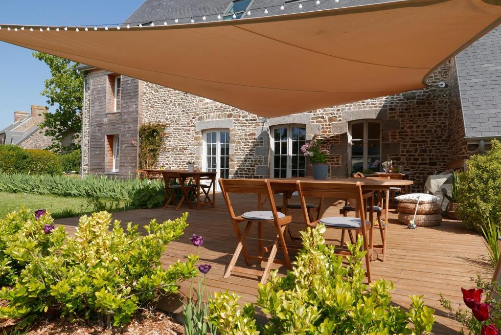 une terrasse en bois avec une table et des chaises sous un grand parasol dans l'établissement Villa de la Plage avec sauna, à Dragey-Ronthon