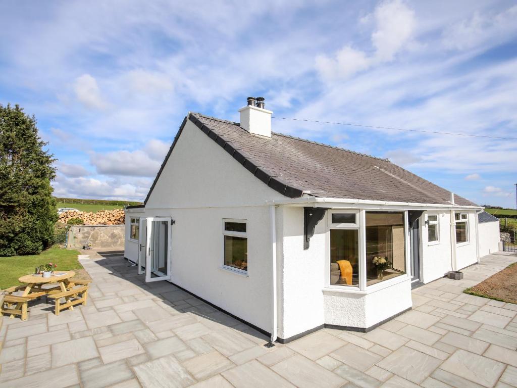 een wit huisje met een patio en een tafel bij Mynydd Mwyn in Llanfairpwllgwyngyll