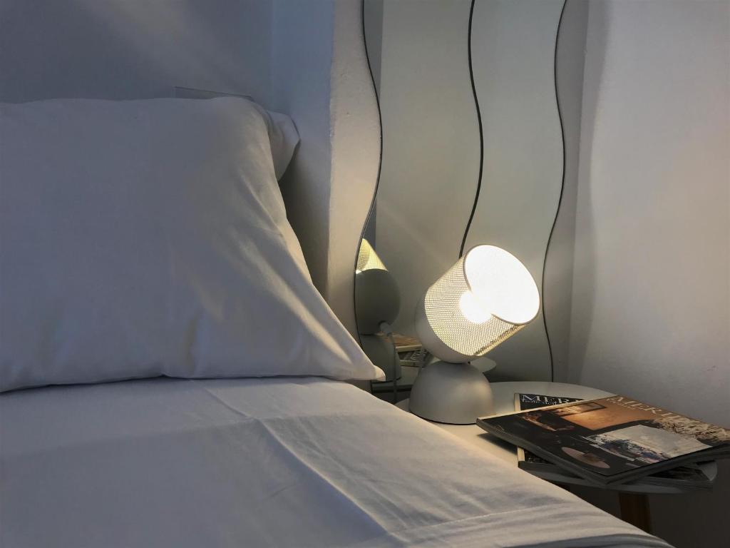 Una cama con una almohada blanca y una lámpara en una mesita de noche en Corte Colori, en Colà di Lazise