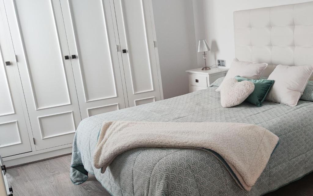 ein Schlafzimmer mit einem Bett mit einer Decke und Kissen in der Unterkunft Piso 100 metros del Centro del Pueblo 6 kilómetros de la PLAYA La BARROSa in Chiclana de la Frontera