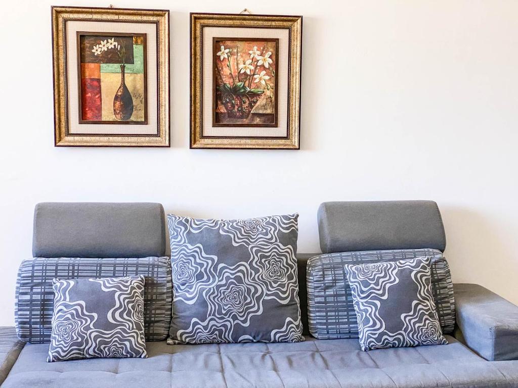 a couch with pillows sitting under two pictures on a wall at The Touristic Promenade Apartment in Hurghada