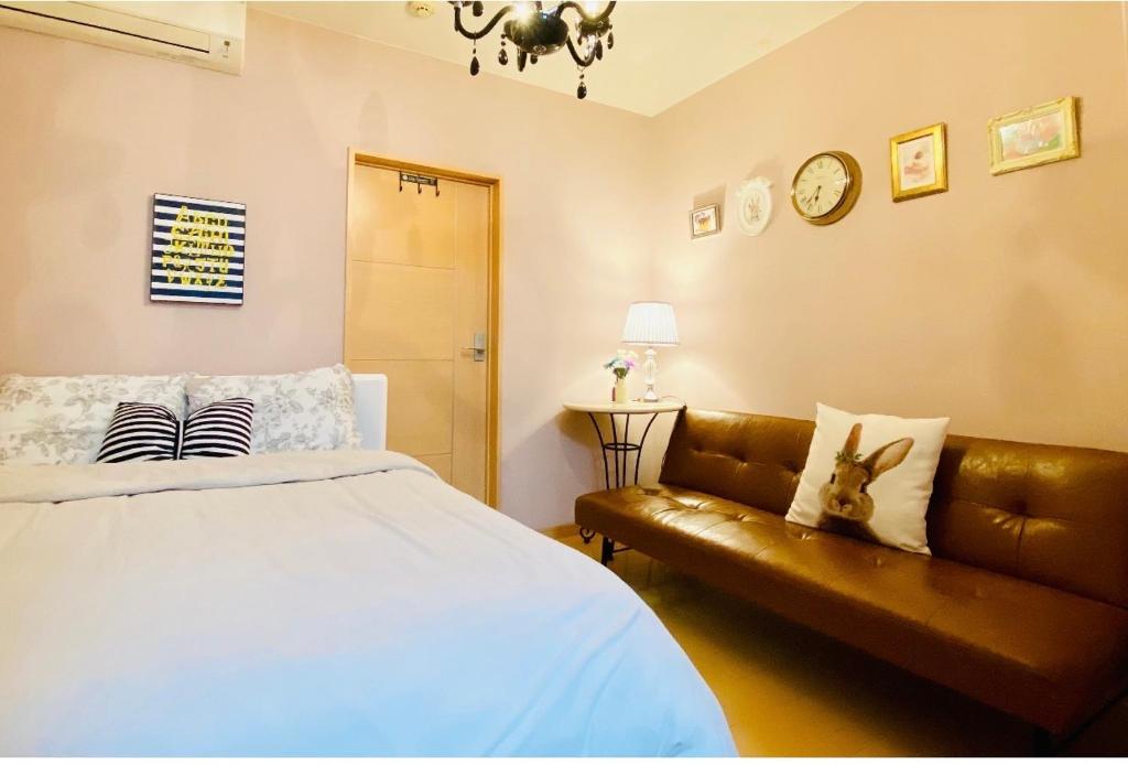 sypialnia z łóżkiem, kanapą i zegarem w obiekcie Mori de house in Kobe 201 w mieście Kobe