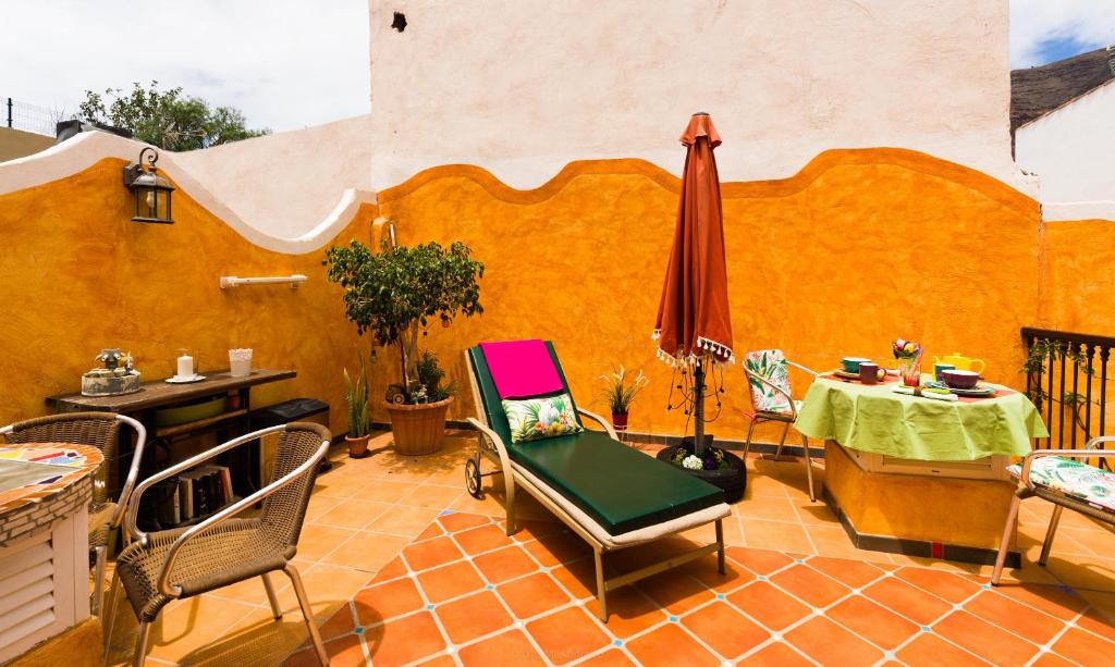 een patio met een tafel en stoelen en een parasol bij Casa Conchilla, La Casita in Valle Gran Rey