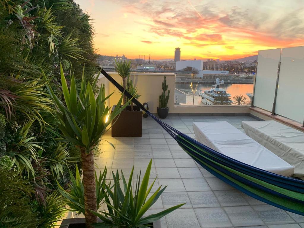 een hangmat op het balkon met een zonsondergang bij 31 Nights Plus Luxury Aircon Beach Apartment Barcelona with Incredible Views in Barcelona
