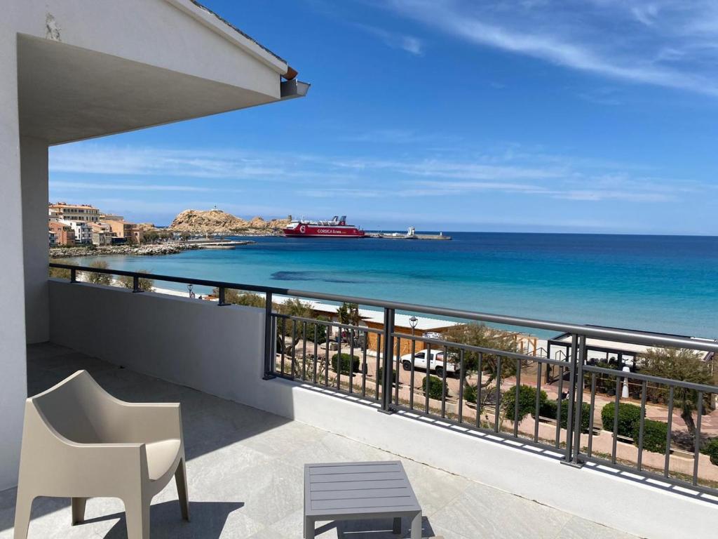 einen Balkon mit Blick auf das Meer und ein Schiff in der Unterkunft Hôtel L'Isula Marina in LʼÎle-Rousse