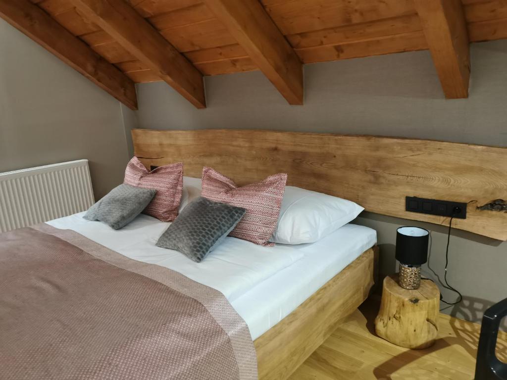 1 dormitorio con cama con cabecero de madera y almohadas en Koliba na vršku en Bytča