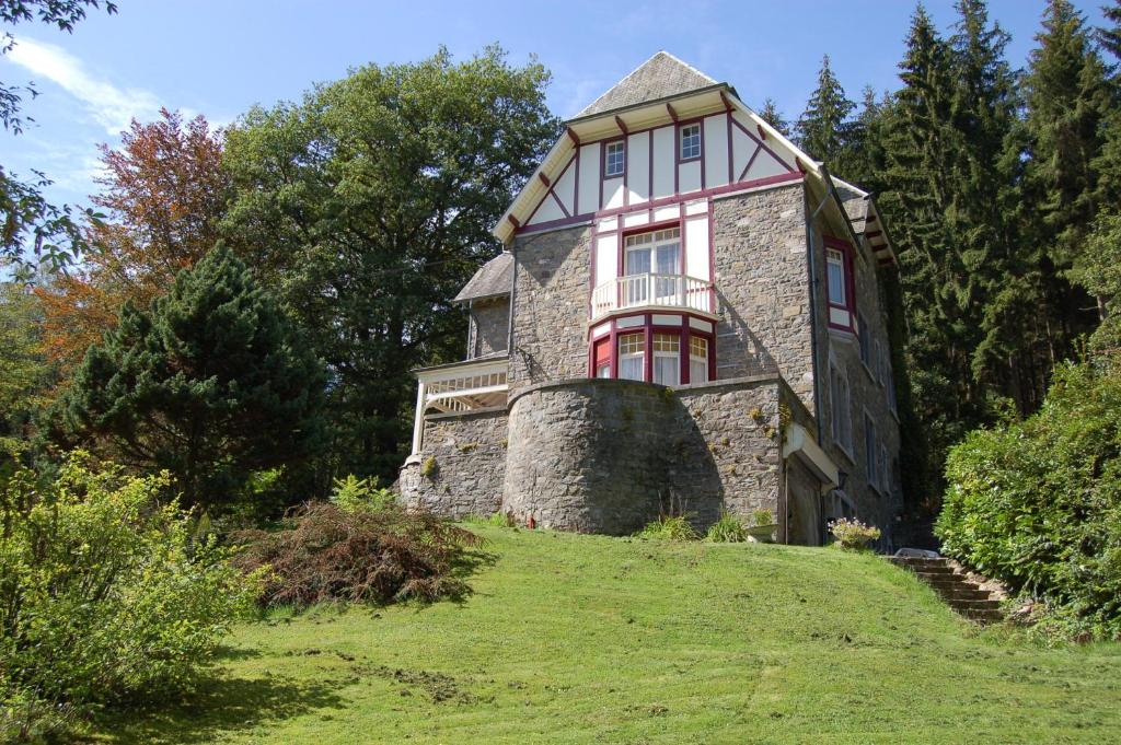 une ancienne maison en pierre sur une colline herbeuse dans l'établissement B&B Les Genêts, à Hatrival