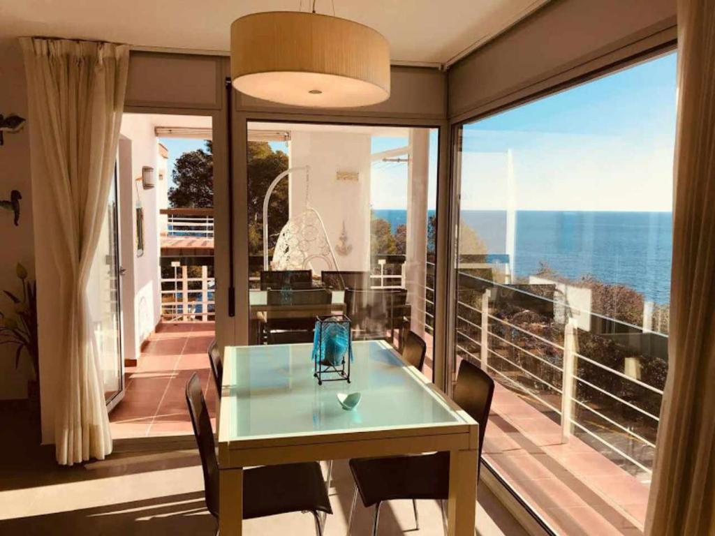 ein Esszimmer mit einem Tisch und Meerblick in der Unterkunft Apartamento Cala Salionç Playa frente a la playa y encima del Mar in Tossa de Mar