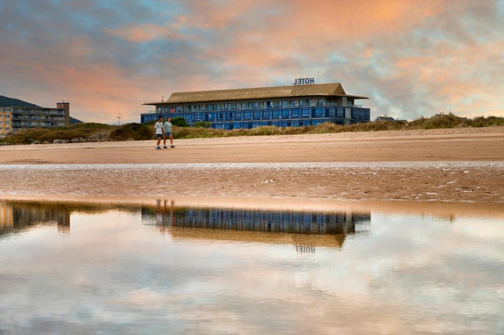 サントーニャにあるHotel Juan de la Cosaの海辺の建物の前に立つ二人