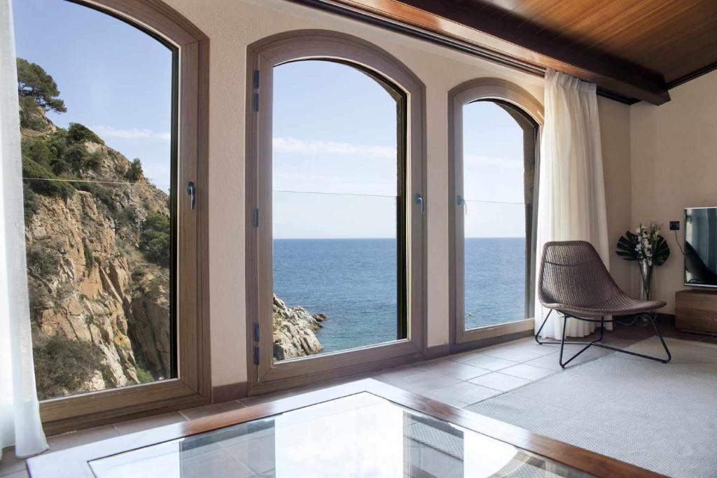 a room with large windows with a view of the ocean at Luxury Rocamar - Primera línea de mar-Terraza in Tossa de Mar