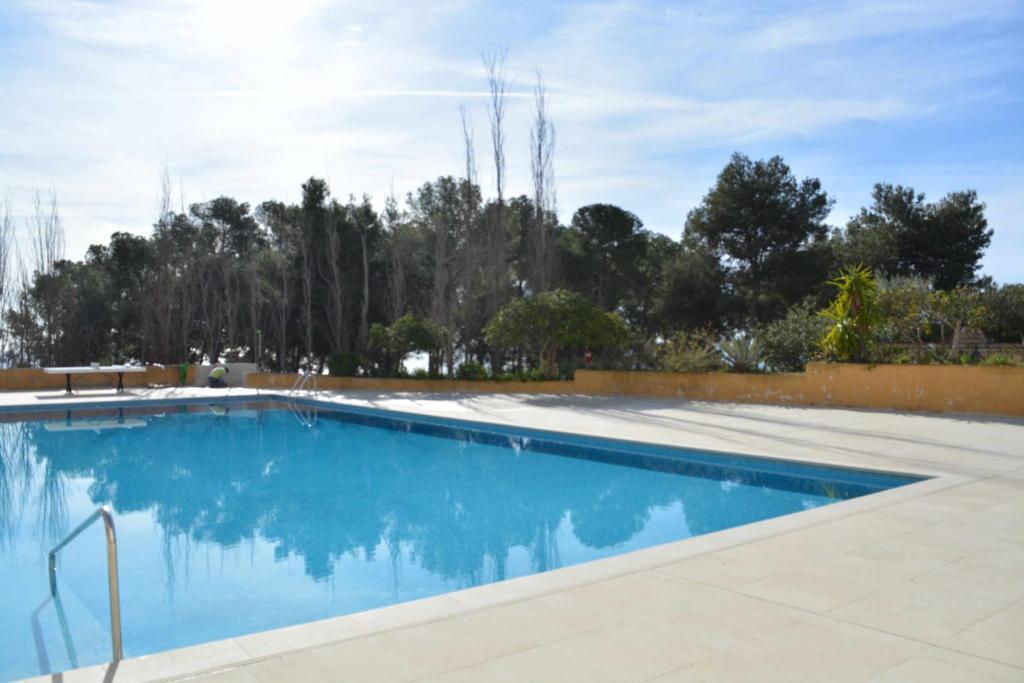 a swimming pool with blue water and trees in the background at Cala LLevado Tossa de M. A/C Parking Piscina in Tossa de Mar