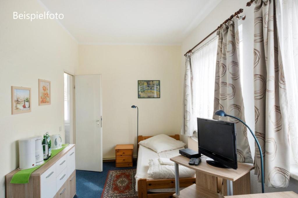 um quarto com uma cama e uma secretária com uma televisão em Pension GP3, Zimmer mit Kochnische und Duschbad vor den Toren Berlins em Dallgow