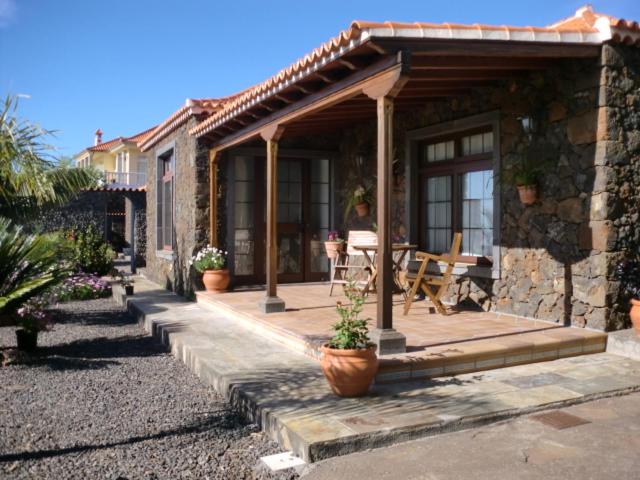 Casa de piedra con porche con mesa y sillas en CASAS COREA, en Puntagorda
