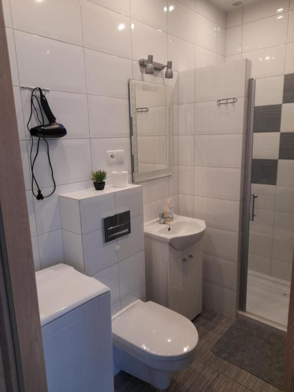 a white bathroom with a toilet and a sink at Apartamenty U Elizy in Kołobrzeg