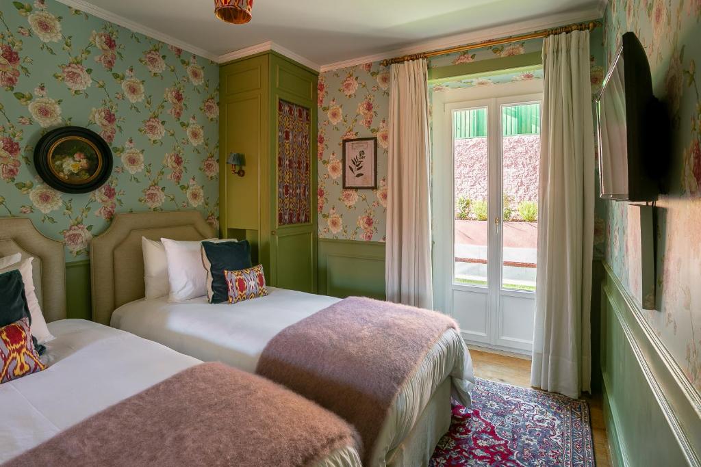 2 Betten in einem Zimmer mit grünen Wänden und einem Fenster in der Unterkunft Rosegarden Essence Sintra - by Unlock Hotels in Sintra