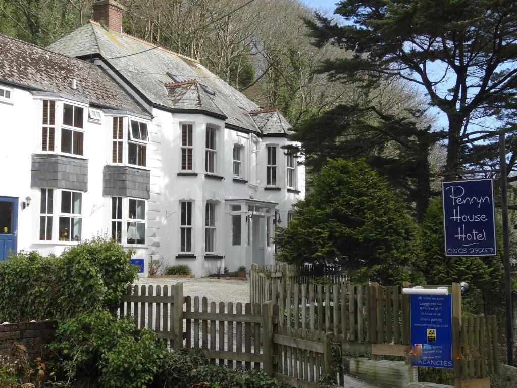 a white house with a wooden fence in front of it at Penryn House Hotel in Polperro