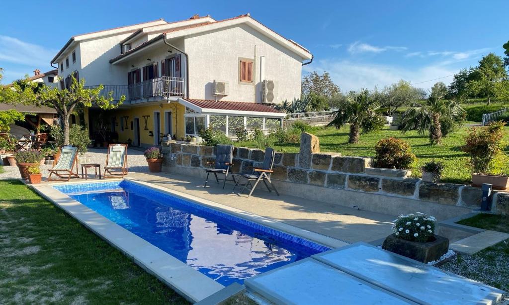 une maison avec une piscine en face d'une maison dans l'établissement Med oljkami Apartment, à Koper