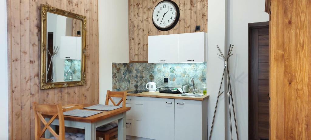 a kitchen with a table and a clock on the wall at 4 STRONY ŚWIATA Pokoje i Apartamenty in Dźwirzyno