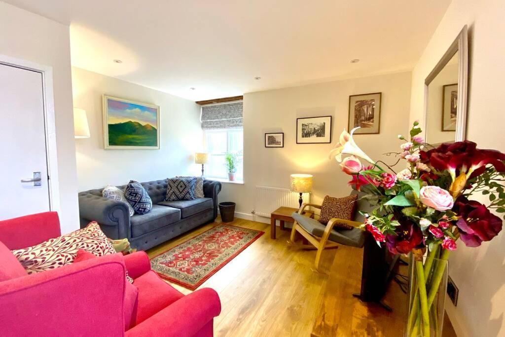 a living room with a blue couch and a vase of flowers at Tilly's a perfect apartment in the Market Town of Ledbury in Ledbury