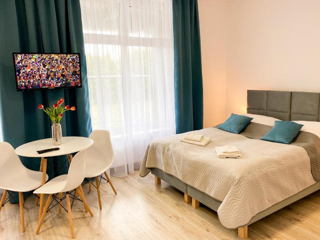 um quarto com uma cama, uma mesa e cadeiras em Bałtycka Osada em Jarosławiec