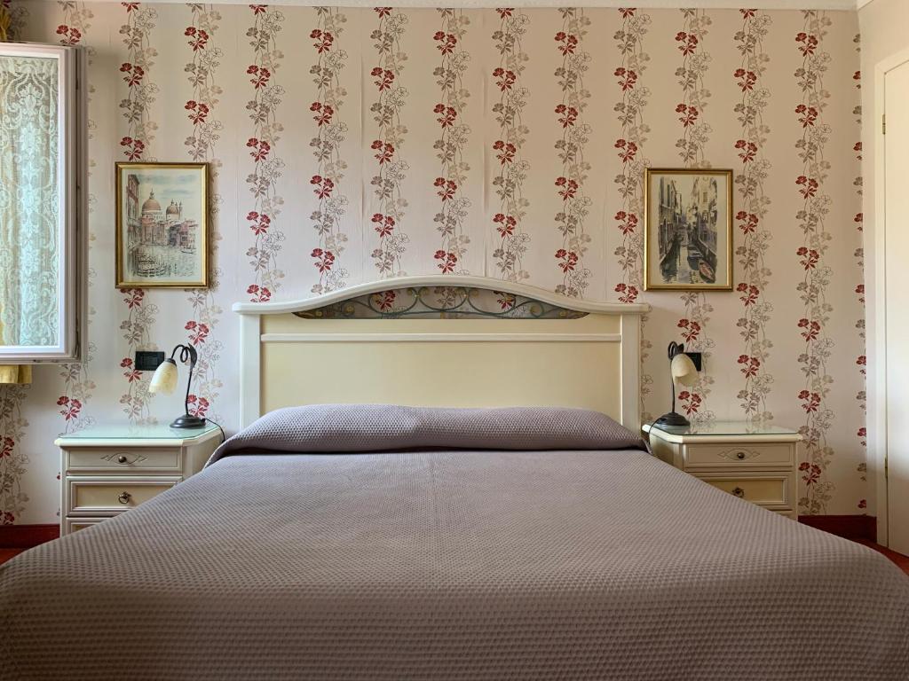 ein Schlafzimmer mit einem Bett mit zwei Nachttischen und zwei Tischen in der Unterkunft AL CAMPANIEL BED AND BREAKFAST in Venedig