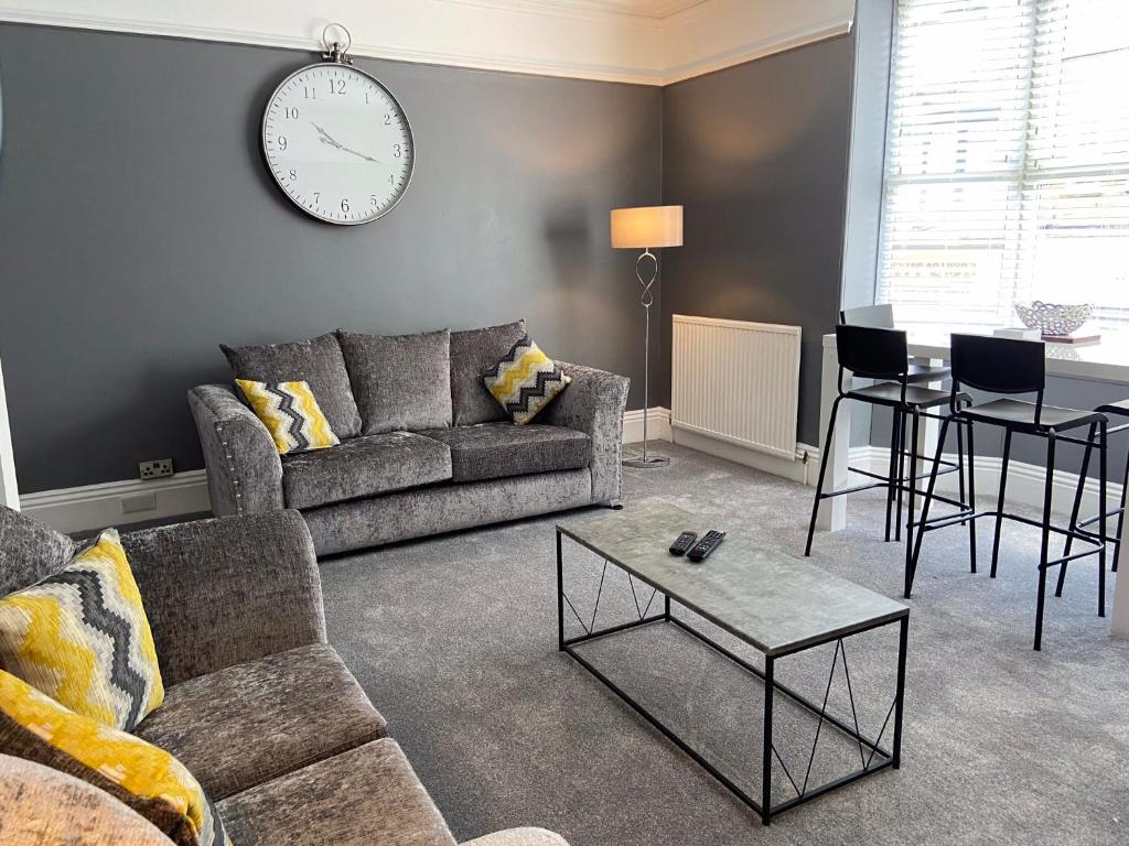 a living room with a couch and a clock on the wall at Bridge street apartment in Bridlington