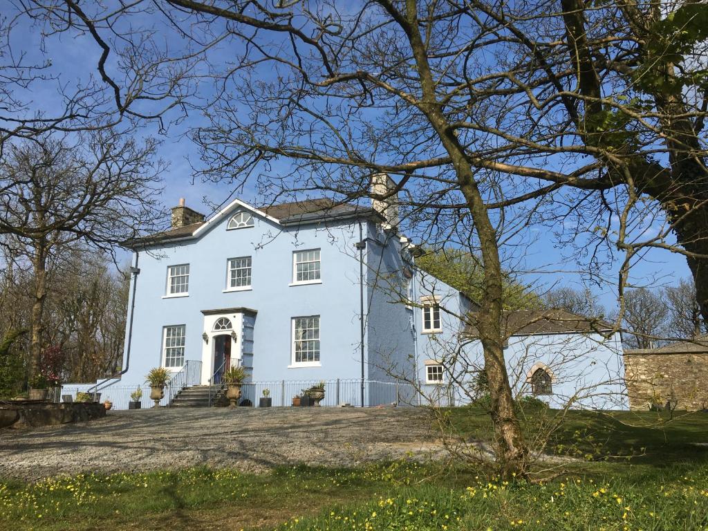 a white house with trees in the foreground at Crug Glas Country House in St. Davids