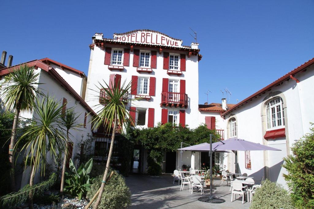 un edificio rojo y blanco con mesas y sillas en Hotel Residence Bellevue, en Cambo-les-Bains