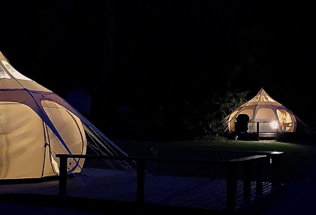 two tents are lit up in the dark at Glamping at Camping La Source in Saint-Pierre-dʼArgençon