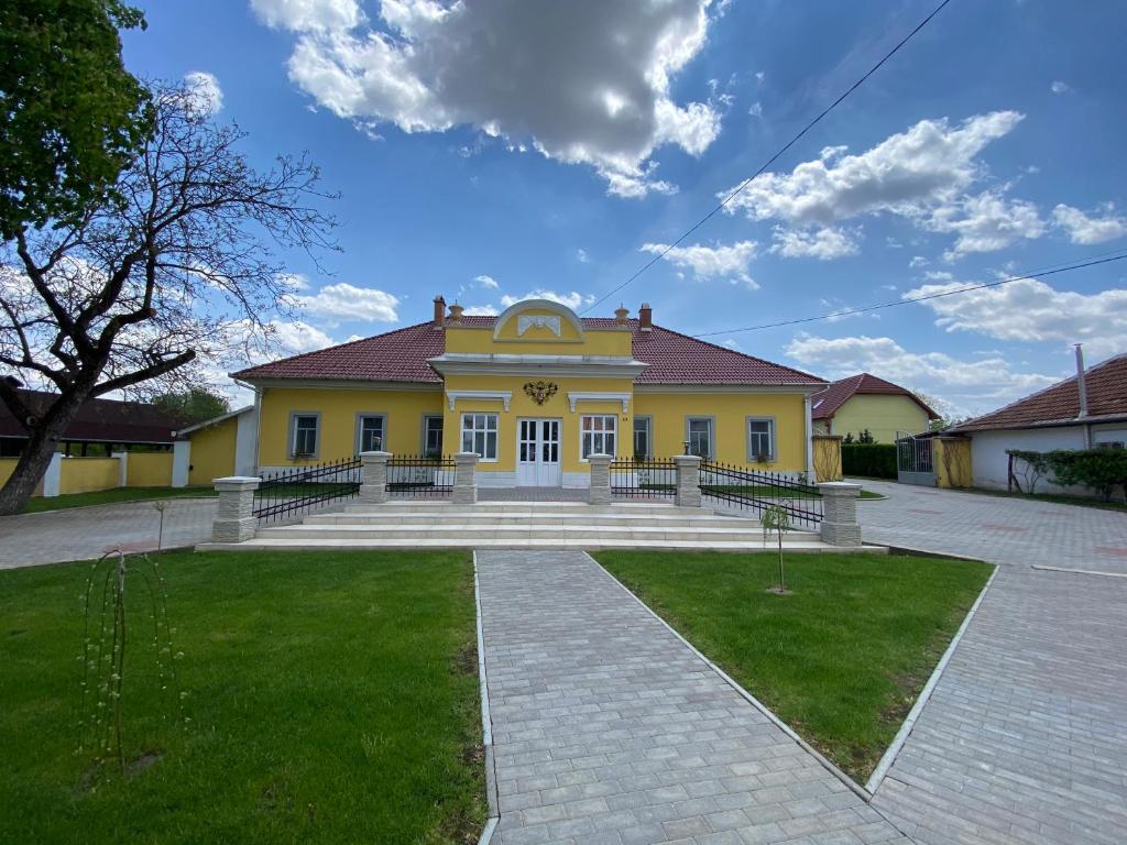 a yellow house with stairs in front of it at Kúria Vendégház in Poroszló