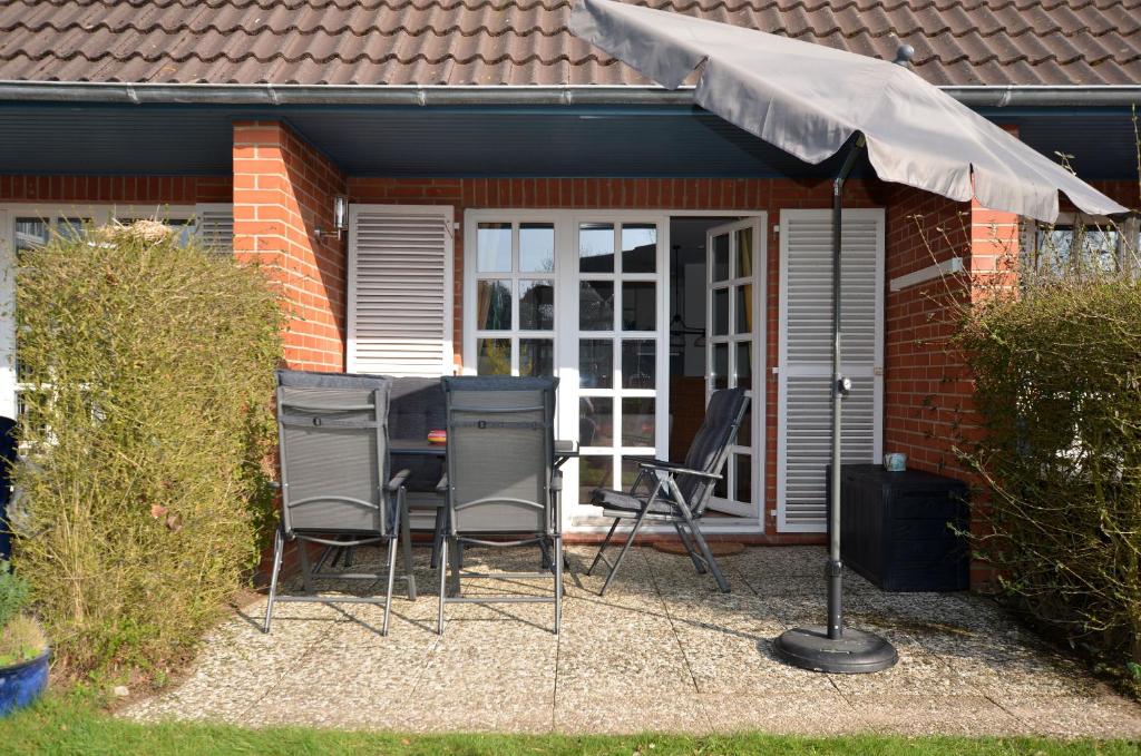 a group of chairs and an umbrella in front of a house at Ewertsen in Wyk auf Föhr