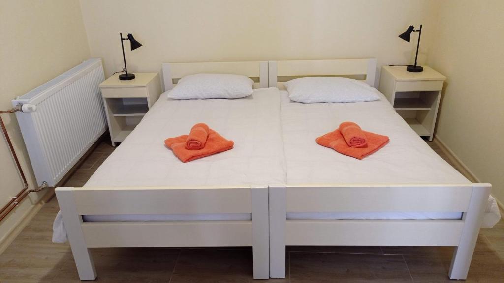 ein weißes Bett mit zwei orangefarbenen Handtüchern darauf in der Unterkunft Apartma Divo Koper in Koper