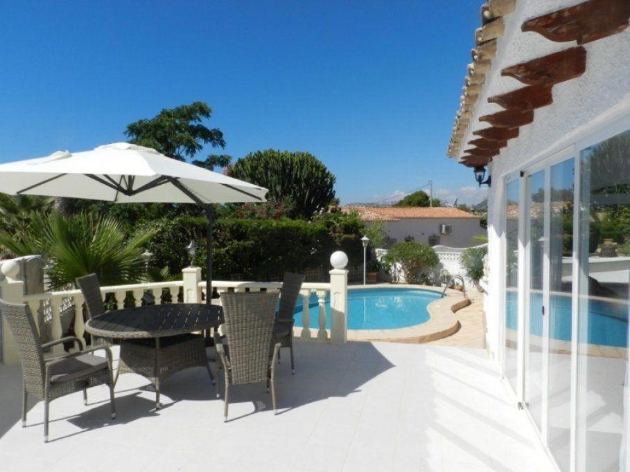 a table and chairs with an umbrella next to a pool at Casa-Zinat in Calpe