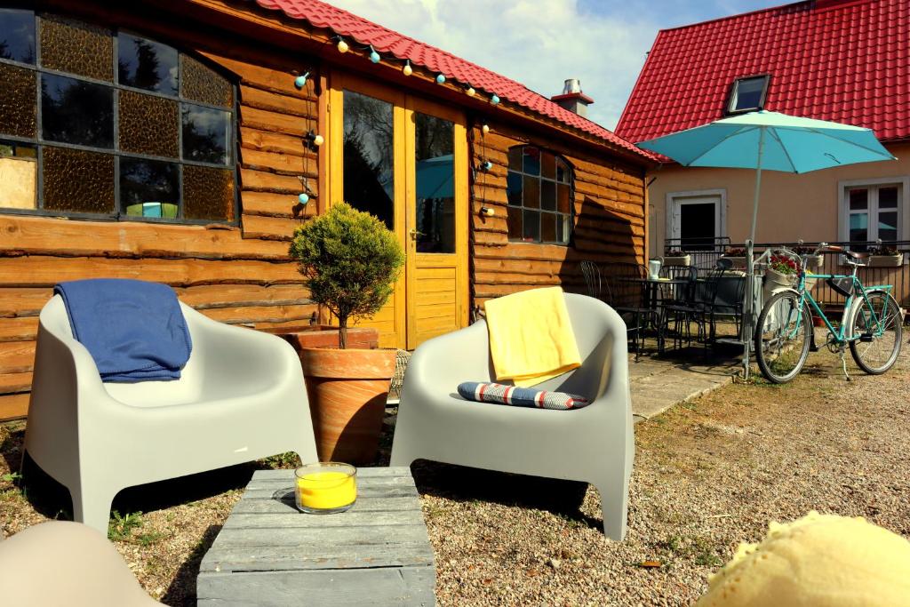 two chairs and an umbrella in front of a cabin at Agroturystyka Gardna Wielka in Gardna Wielka