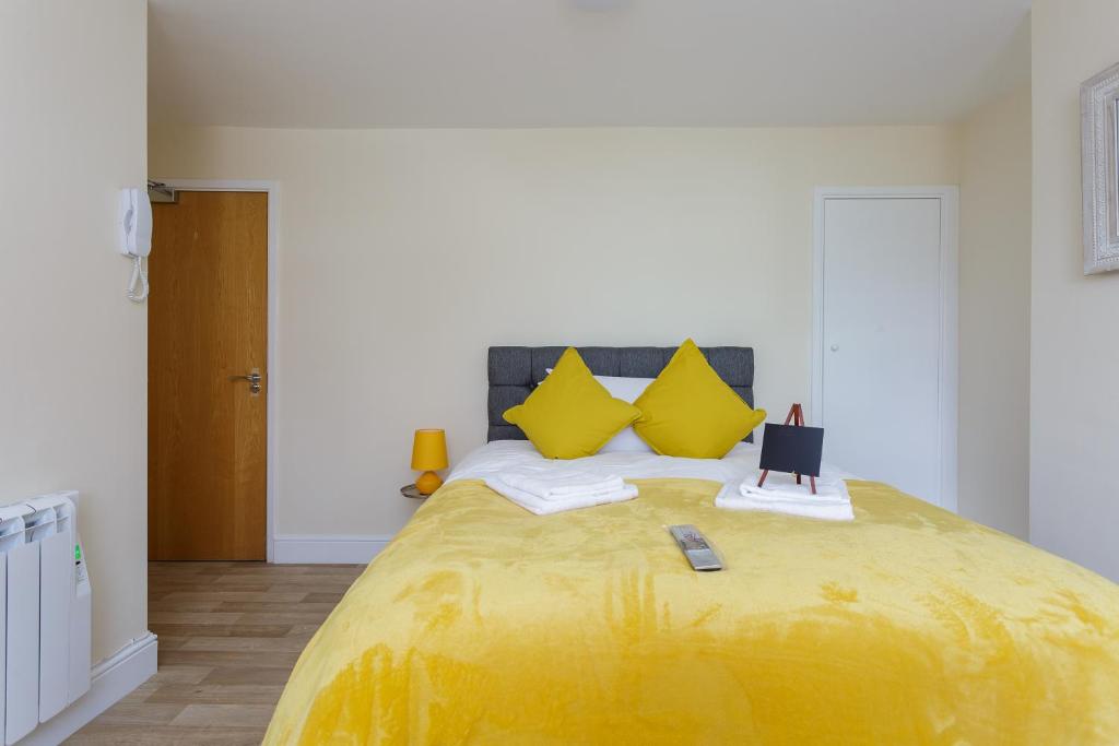 una camera da letto con un grande letto giallo con cuscini gialli di St Mary's - Modern Central Huge Studio Apartments a Southampton