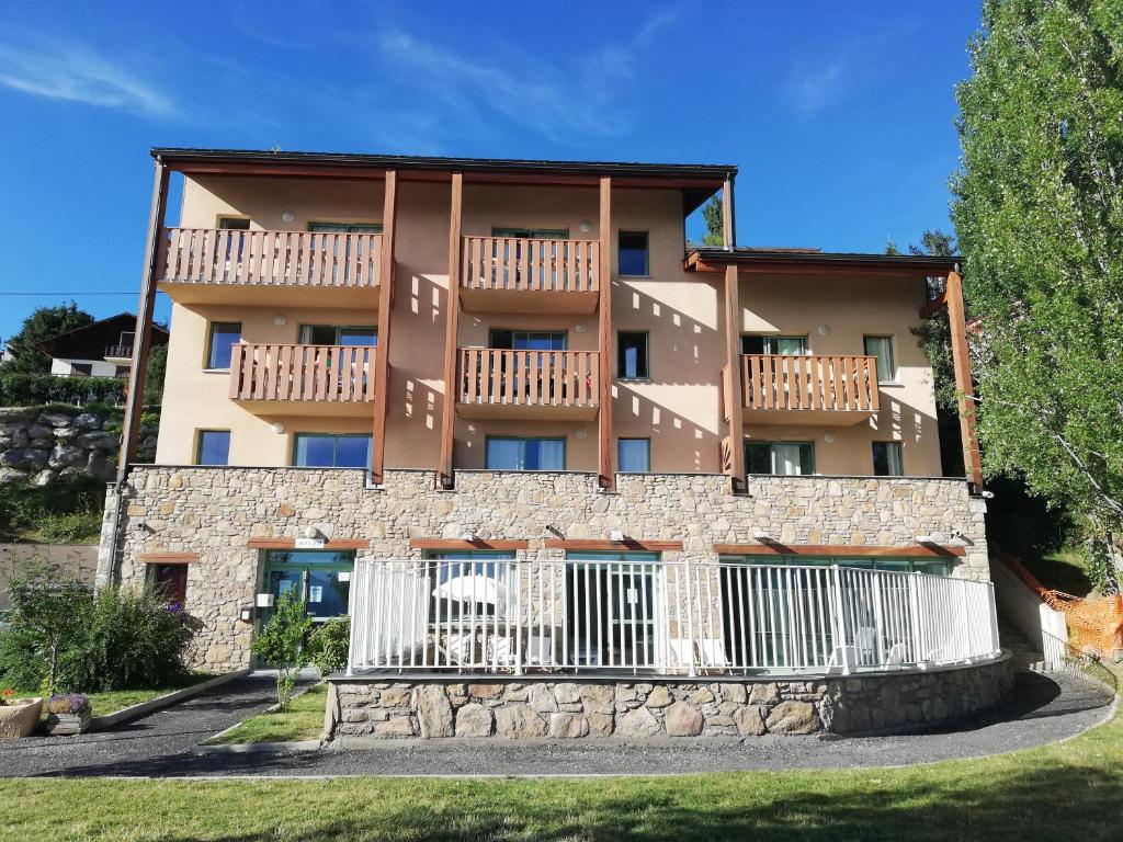 un immeuble d'appartements avec des balcons en bois et une clôture dans l'établissement Résidence Néméa Les Chalets Du Belvédère, à Font-Romeu