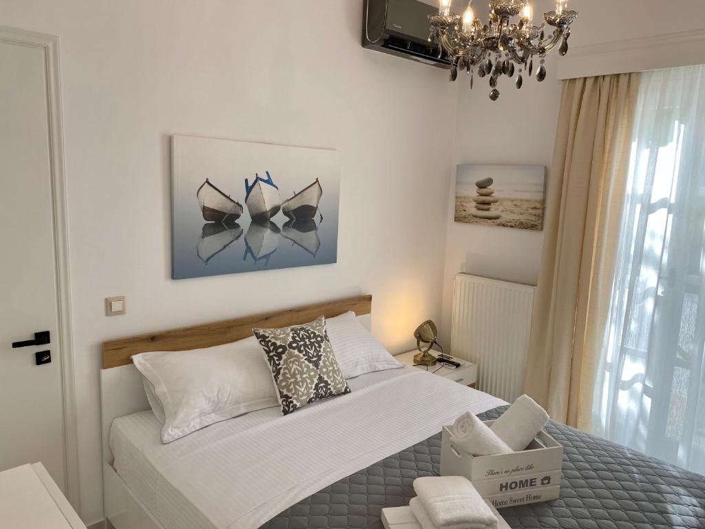 a bedroom with a white bed and a chandelier at PORTA HOME modern and hospitable in Naxos Chora