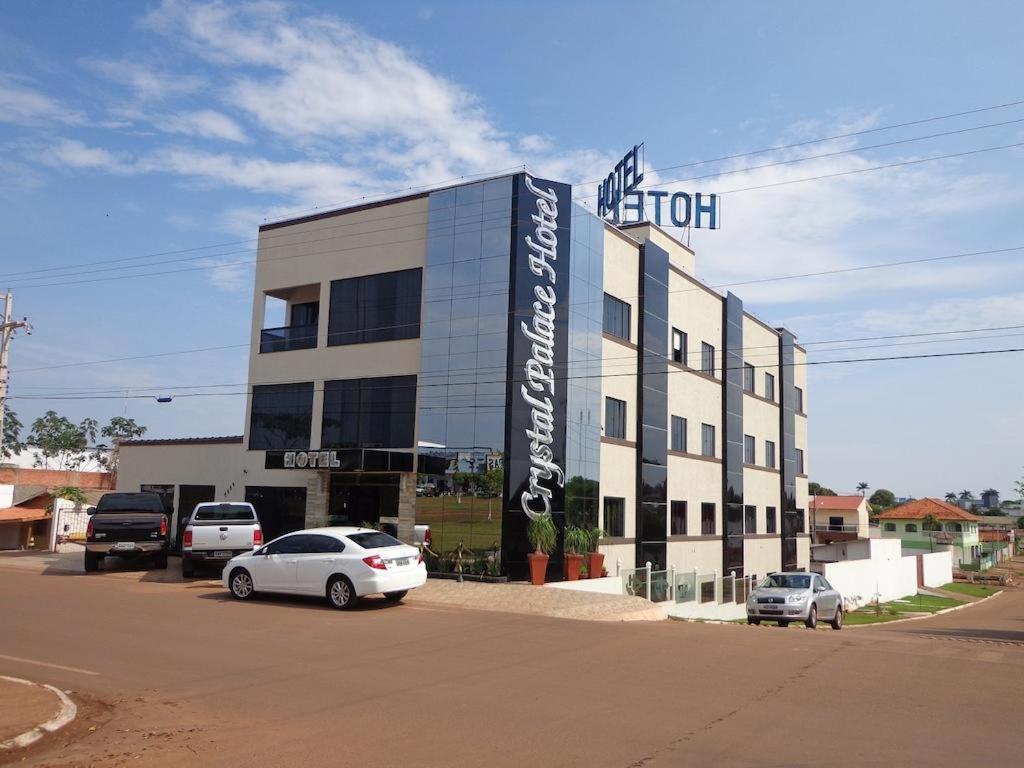 a hotel with two cars parked in front of it at Crystal Palace Hotel in Rolim de Moura