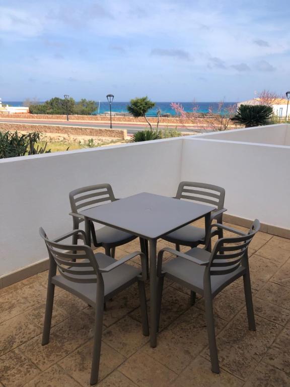 een tafel en stoelen op een balkon met uitzicht op de oceaan bij Apartamento Es Calo (Edificio Cavall de Llevant) in Es Calo