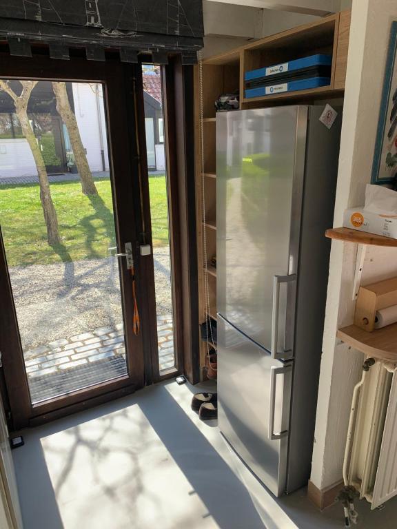 a kitchen with a refrigerator and a sliding glass door at Ysermonde Fisherman's Cottage in Nieuwpoort