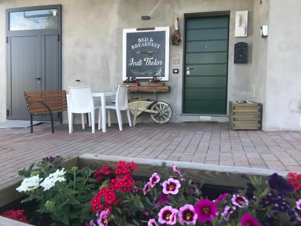 eine Terrasse mit einem Tisch, Stühlen und Blumen in der Unterkunft Bed & Breakfast Indi Thelar in Villa Guardia