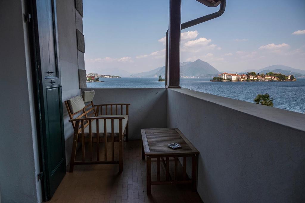 a balcony with two chairs and a table and a view of the water at Hotel Villa Ruscello in Baveno