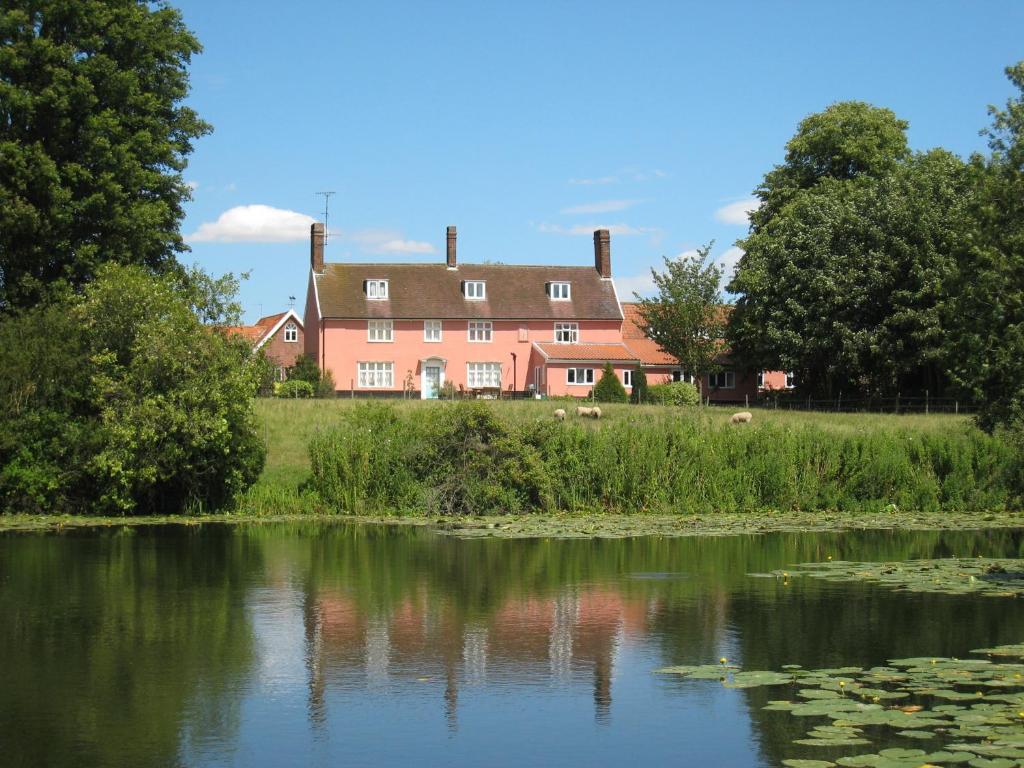 a house on a hill next to a body of water at Colston Hall Farmhouse B&B in Framlingham