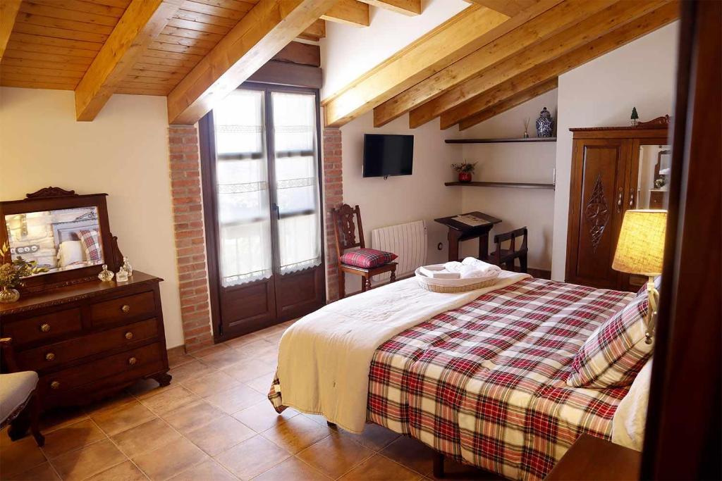 a bedroom with a bed and a dresser and a television at Casa Rural La Tayuela in Luanco