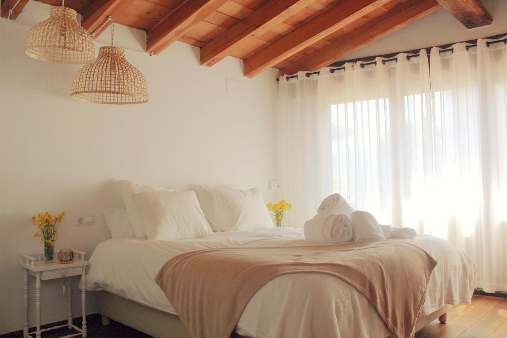 El Niu Casa Rural في Montagut: غرفة نوم بسرير وملاءات بيضاء ونافذة
