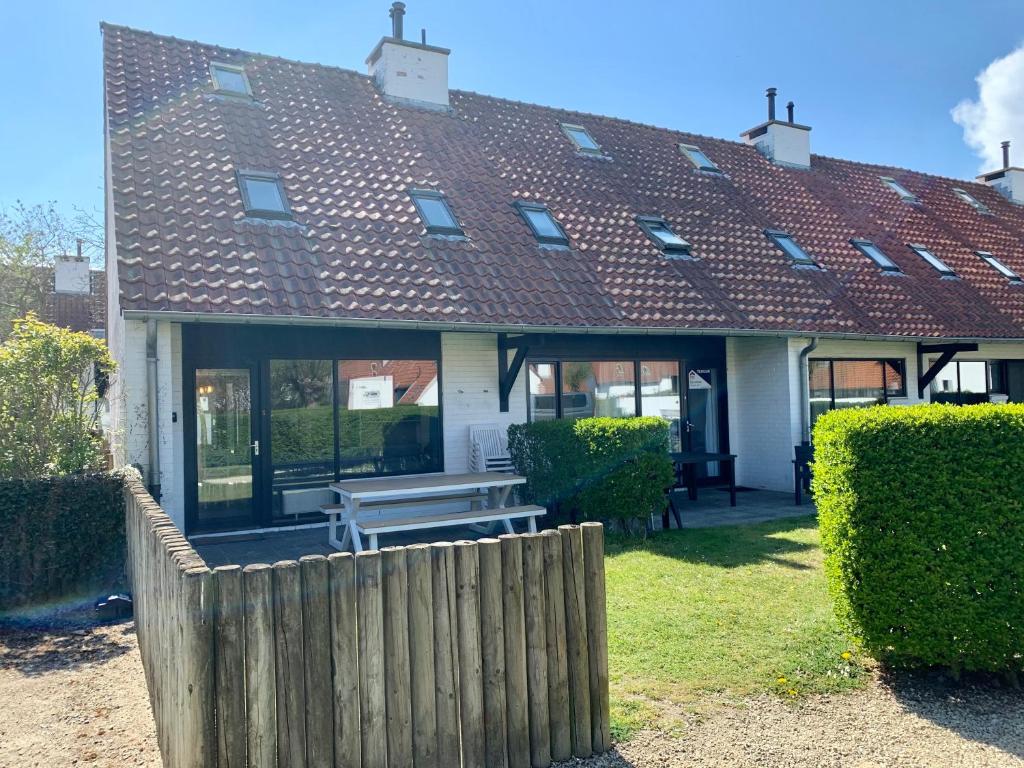 a house with a wooden fence in front of it at Ysermonde Fisherman's Cottage in Nieuwpoort