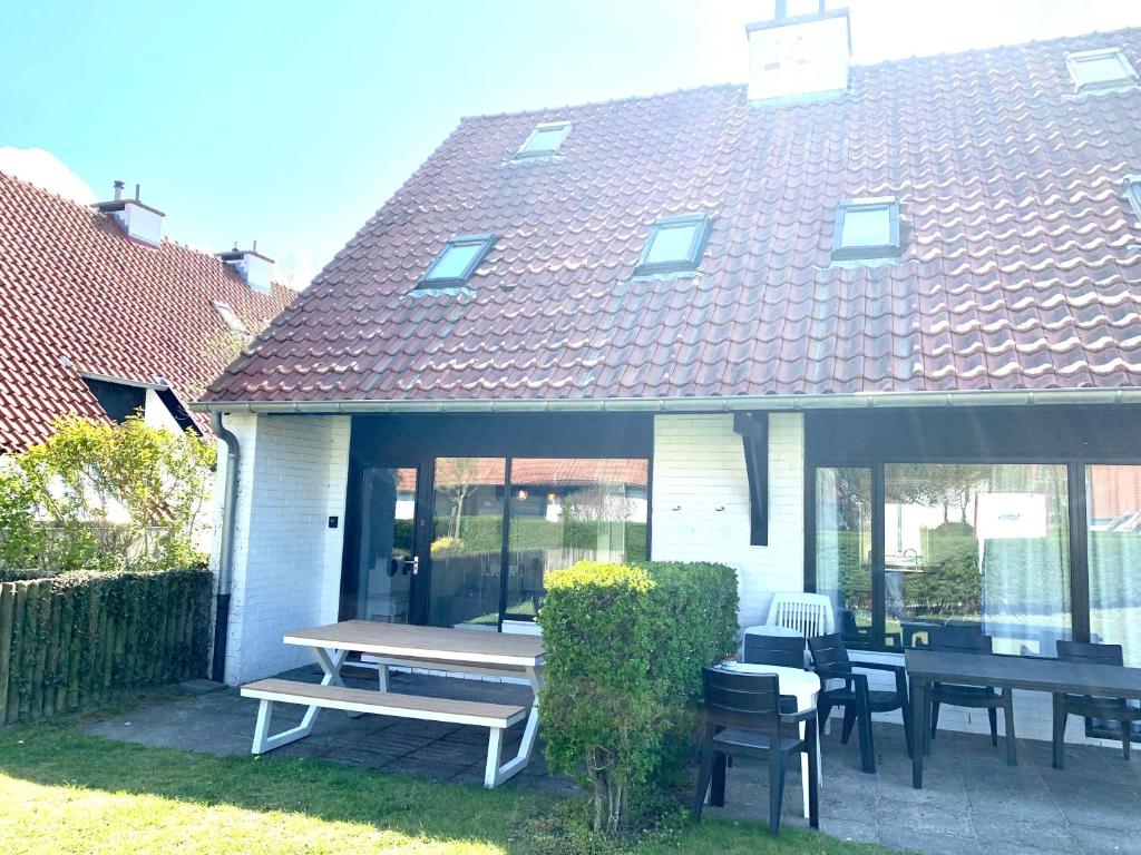 a house with a picnic table and chairs in the yard at Ysermonde Fisherman's Cottage in Nieuwpoort